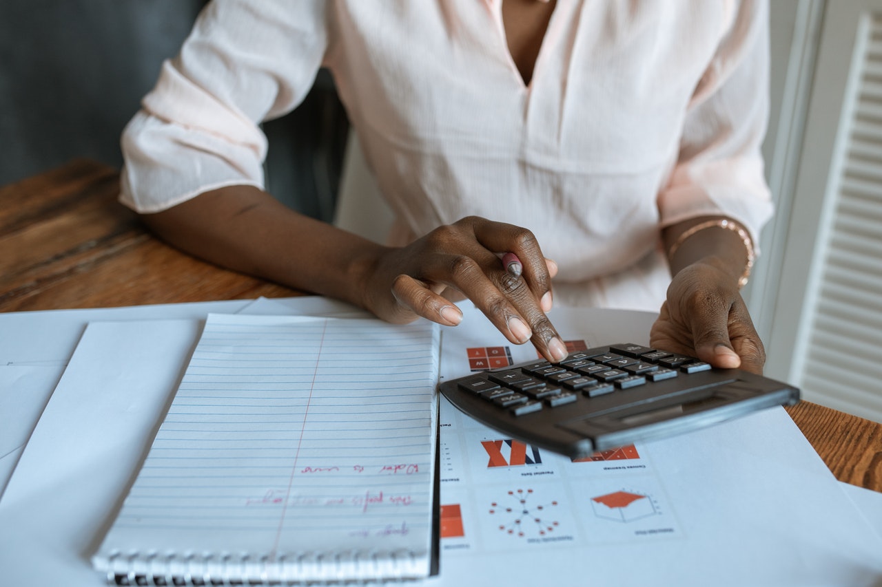 woman sitting at desk with notebook using calculator