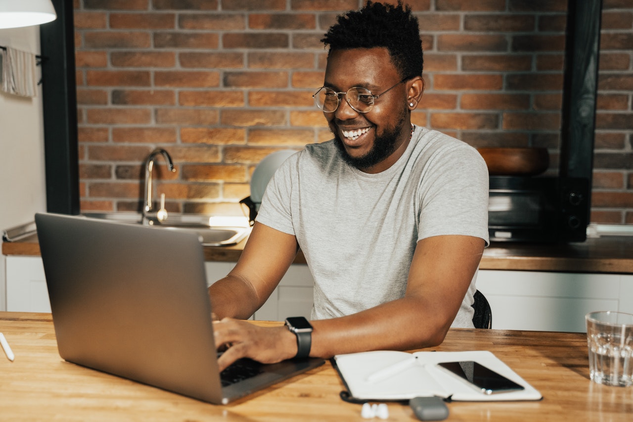 smiling man in kitchen setting using laptop